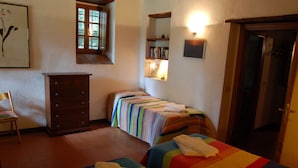 A bedroom with two beds, a dresser, a chair, a bookshelf, and a door. - Appartamento Beatrice - Apartment with pool (Monsanto I)