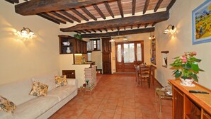 A living room with a sofa, a coffee table, and a dining area with chairs and a table. - Casa Stefy - Apartment in Cortona, Tuscany (Cortona)