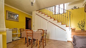 Un coin repas avec une table dressée pour quatre personnes, un escalier et un mur jaune.