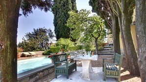 Un espace extérieur aménagé avec des sièges, une piscine, des arbres et un mur en pierre.