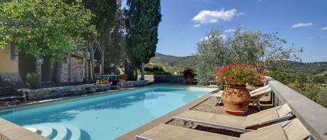 A swimming pool with lounge chairs and potted plants.
