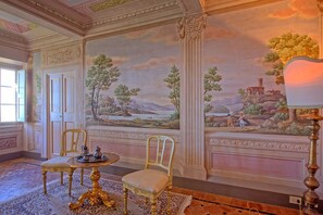 Classic design with a serene landscape mural, elegant chairs, and a patterned rug.