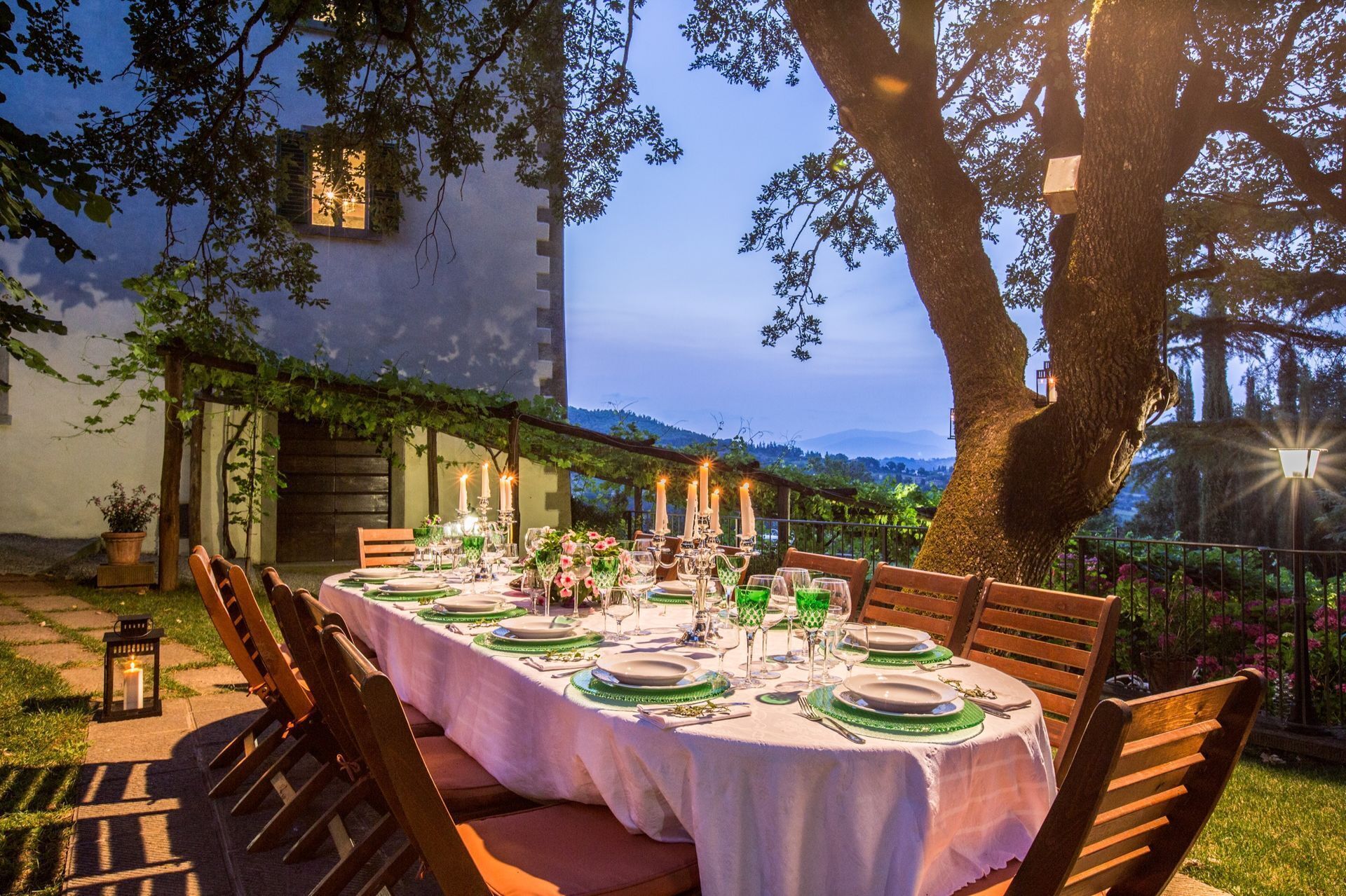 An outdoor dining area with a table set for six, surrounded by wooden chairs.