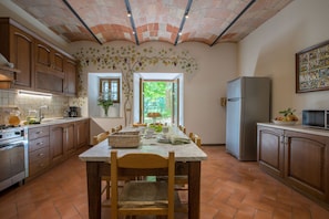 A kitchen with a dining table, chairs, and a refrigerator.