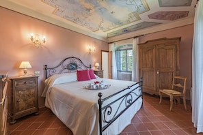 A bedroom with a bed, bedside lamps, a wooden wardrobe, and a window with curtains.