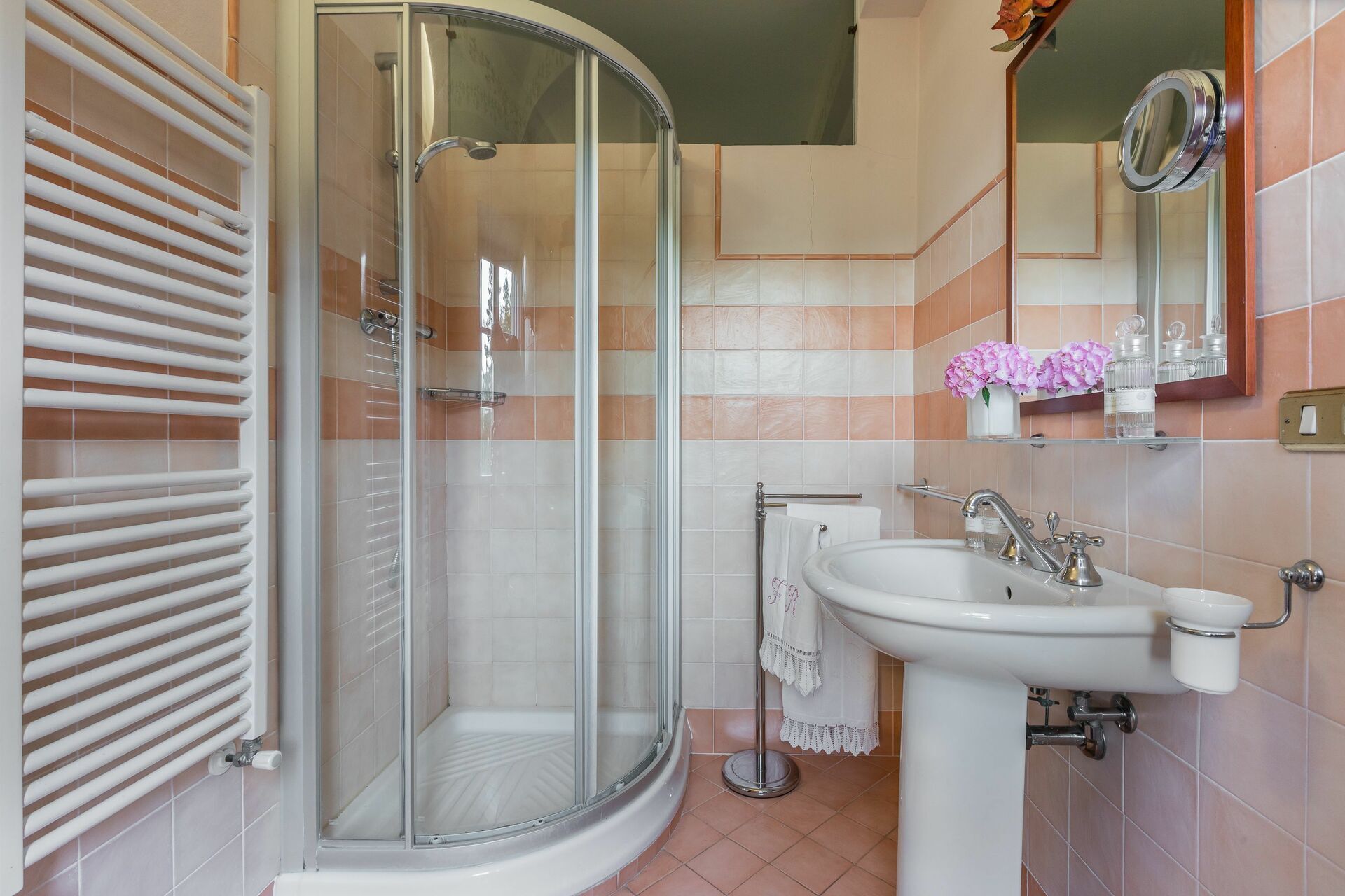 A modern bathroom with a glass shower enclosure, a pedestal sink, and a vanity with a mirror.