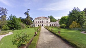 A large, symmetrical building with a central courtyard, surrounded by manicured lawns and potted plants.