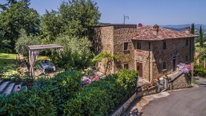 A stone building with a tiled roof, surrounded by lush greenery and a garden with flowers. - Torre del Cielo - Luxury Villa with private pool (Monterchi)