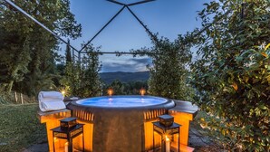 A hot tub with two side benches and two lanterns, surrounded by a wooden deck and garden. - Torre del Cielo - Luxury Villa with private pool (Monterchi)