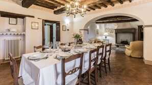 A dining area with a long table set for a meal, wooden beams on the ceiling, and a fireplace in the background. - Torre del Cielo - Luxury Villa with private pool (Monterchi)