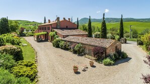 Uma vila tradicional com entrada por caminho de pedras, rodeada por vegetação exuberante e uma vista panorâmica do campo.