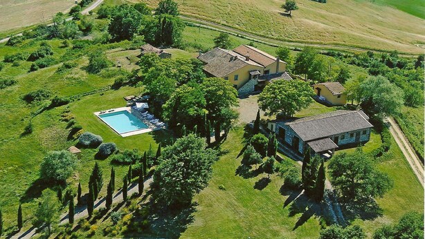 Vista aérea de una propiedad con piscina, varias edificaciones y abundante vegetación.