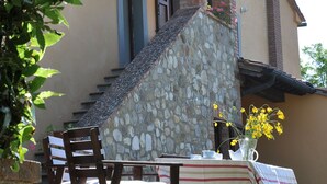 Un muro de piedra con un banco de madera y una mesa con mantel a rayas.