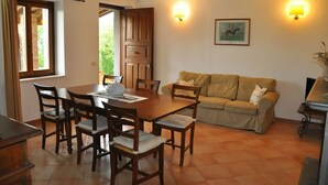 Un comedor con una mesa y sillas de madera, un sofá color beige y dos lámparas de pared.