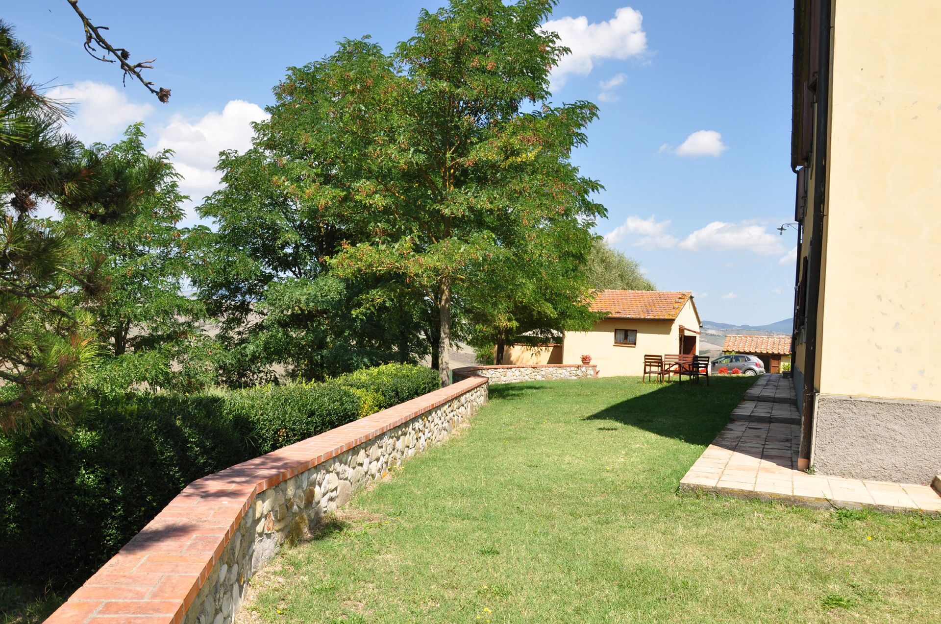 A stone retaining wall, a grassy lawn, and a small building with a tiled roof.