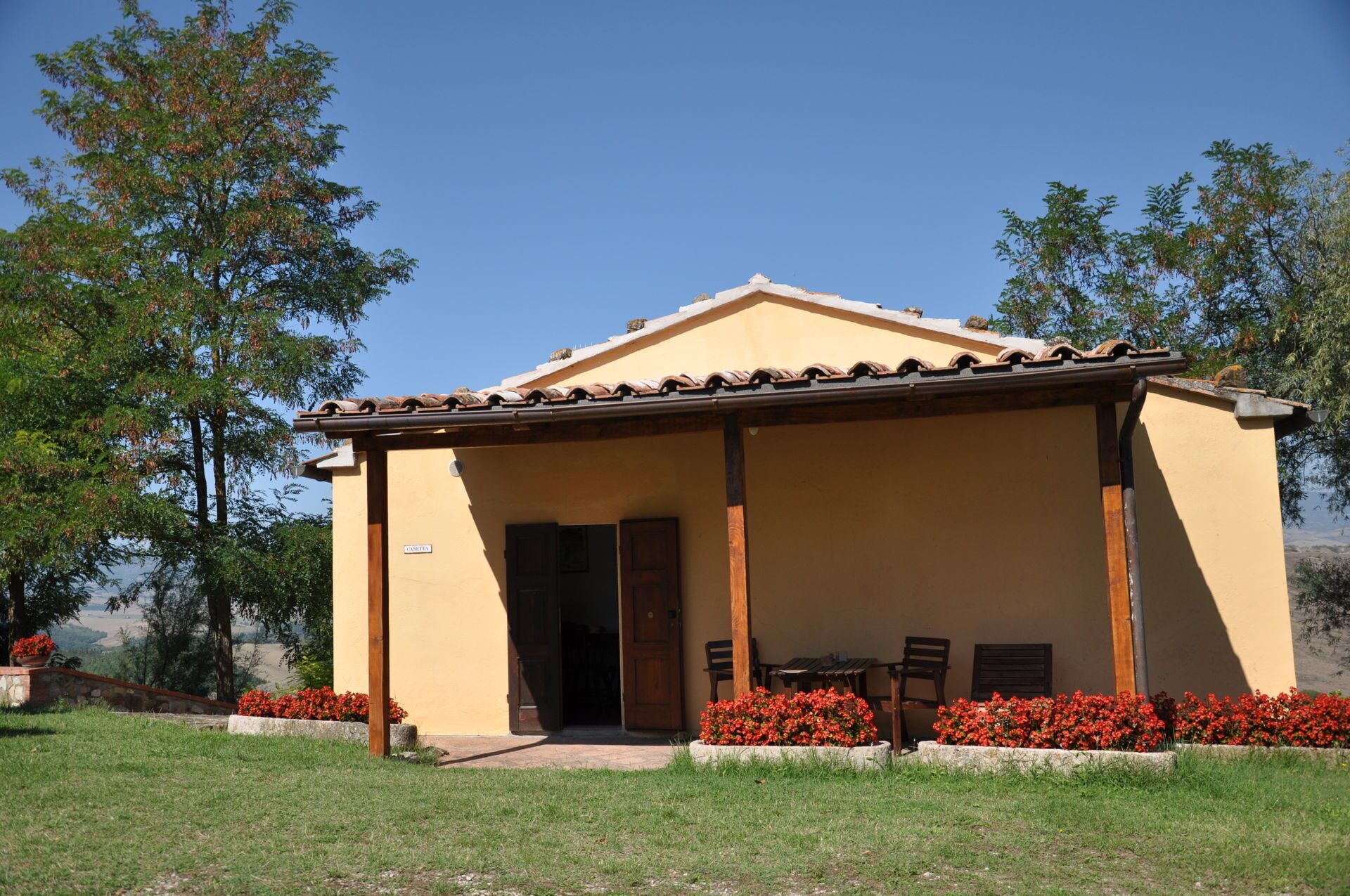 Un edifici petit amb teulada de rajola i un porxo cobert. Hi ha dues portes i una taula petita amb caires a l'exterior.