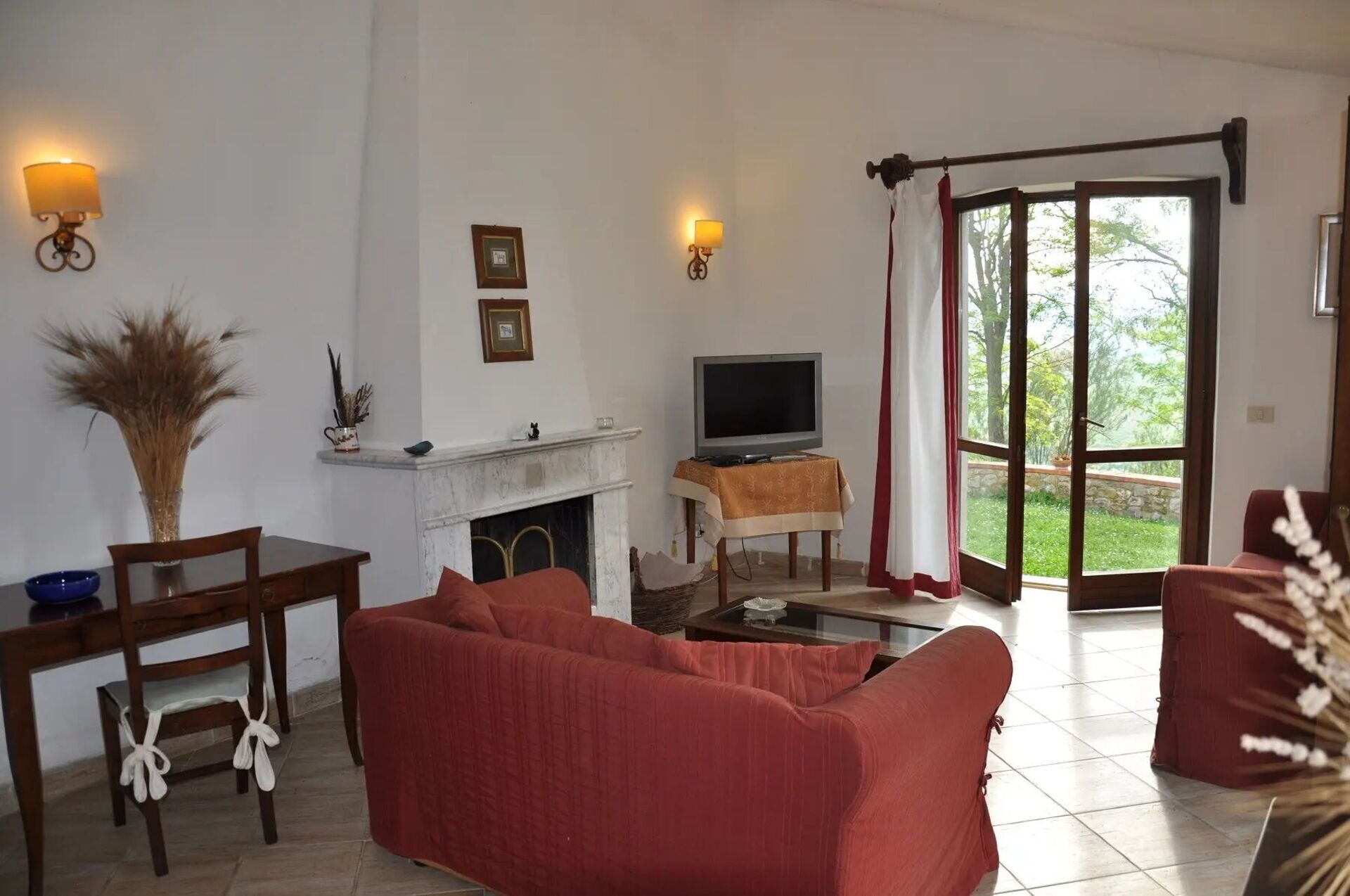 A living room with a sofa, a television, a fireplace, and a dining area with chairs and a table.
