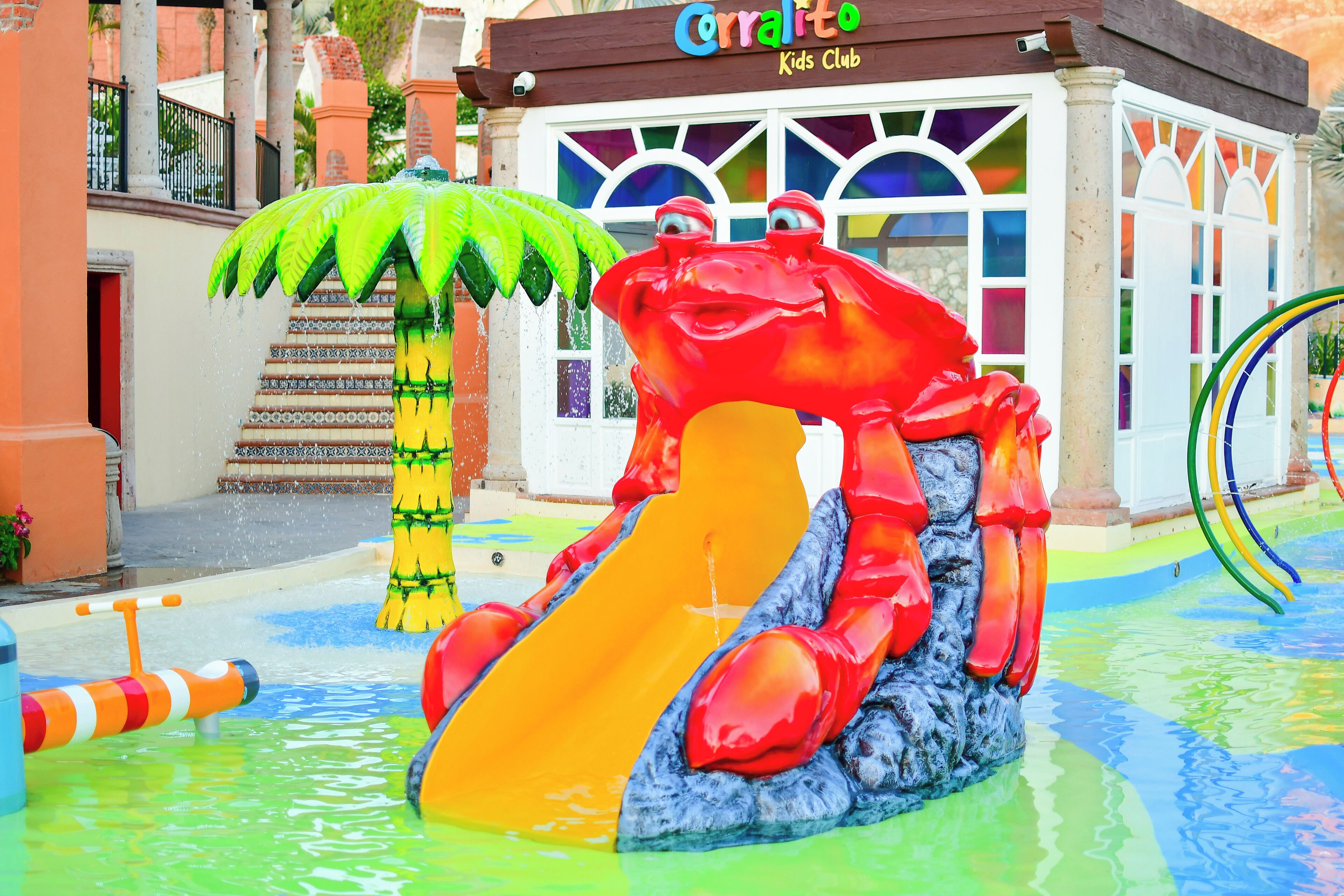 A water park with a large red crab slide and a green palm tree.