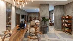 A modern lobby with a wooden reception desk, comfortable seating, a large potted plant, and a bookshelf. - El Encanto All Inclusive Resort at Hacienda Encantada (Cabo San Lucas)