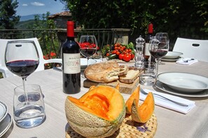 A table set for a meal with a bottle of wine, glasses, bread, and a halved melon. - Villa Lucolena - Villa with private pool (Lucolena In Chianti)