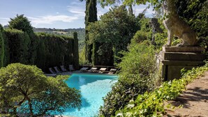 Une piscine entourée d’une végétation luxuriante et de statues en pierre.