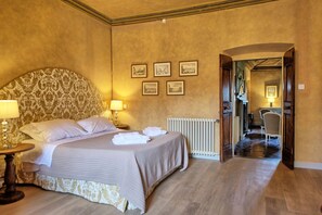 Ein Hotelzimmer mit einem großen Bett, zwei Nachttischlampen, einer Heizung und gerahmten Bildern an der Wand.