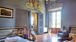 Une pièce avec un lit, une chaise et une grande fenêtre.