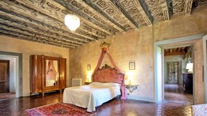 Une chambre spacieuse avec un grand lit, un plafond décoré et une armoire en bois de style traditionnel.