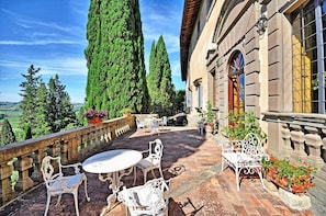 A terrace with outdoor furniture, a stone balustrade, and potted plants. - Montegufoni 19b - Apartment with swimming pool (Montespertoli)