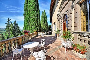 A terrace with outdoor furniture, a stone balustrade, and potted plants.