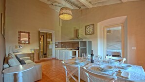 Un coin repas avec une table dressée pour quatre personnes, un canapé, une lampe et un luminaire suspendu.