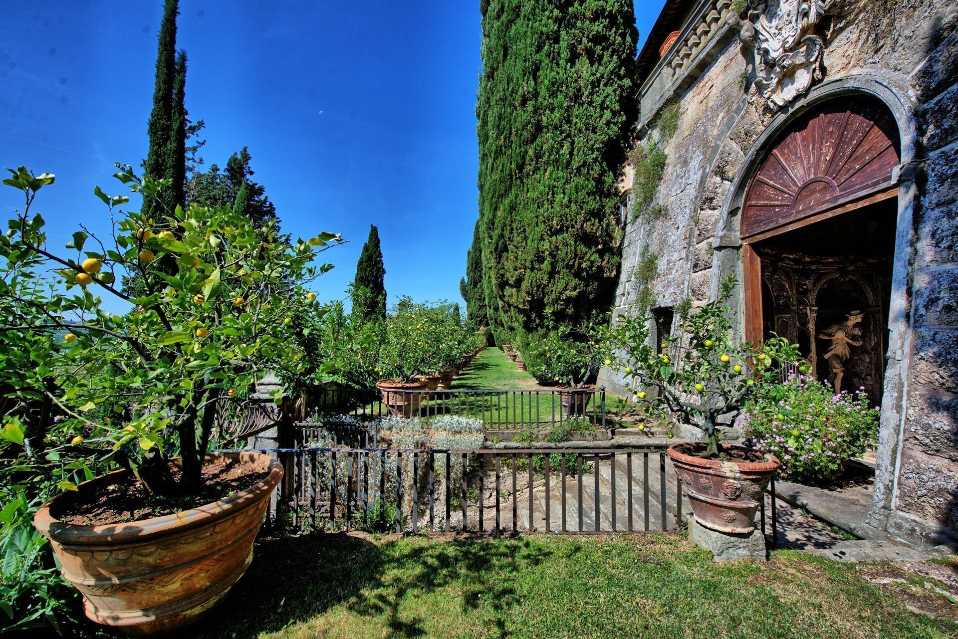 A garden with potted plants and a stone building with an arched entrance.