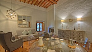 Una sala de estar con una mesa redonda de vidrio, un sofá, una silla y un mueble aparador.
