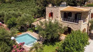 A stone villa with a swimming pool, surrounded by lush greenery and trees. - Villa Nipos - Villa Rental on the Island of Crete, Greece (Vrýsai)