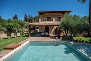 Un bâtiment en pierre de deux étages, doté d’une piscine, d’un espace extérieur aménagé et d’une terrasse couverte.