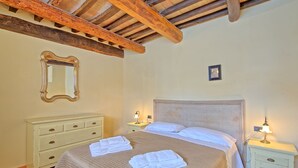 Ein Schlafzimmer mit einem Bett, zwei Nachttischen, einer Kommode, einem Spiegel und einem gerahmten Bild an der Wand.