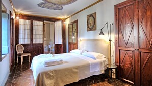 A hotel room with a large bed, wooden wardrobe, and a chandelier. - Cappella - Apartment with swimming pool (Montespertoli)