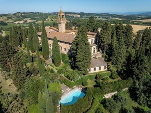 Vue aérienne d’un vaste domaine comprenant une tour imposante, de vastes espaces verts et une piscine.