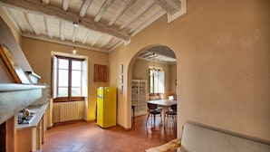 Eine Küche mit einem gelben Kühlschrank, ein Essbereich mit Tisch und Stühlen sowie eine hölzerne Bank.