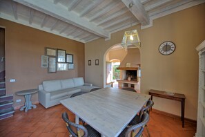 Un salón amplio con una gran mesa de madera, un sofá blanco y sillas de mimbre.