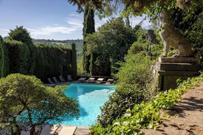 A pool surrounded by lush greenery, stone statues, and a clear view of the landscape. - Montegufoni 18 - Apartment with swimming pool (Montespertoli)
