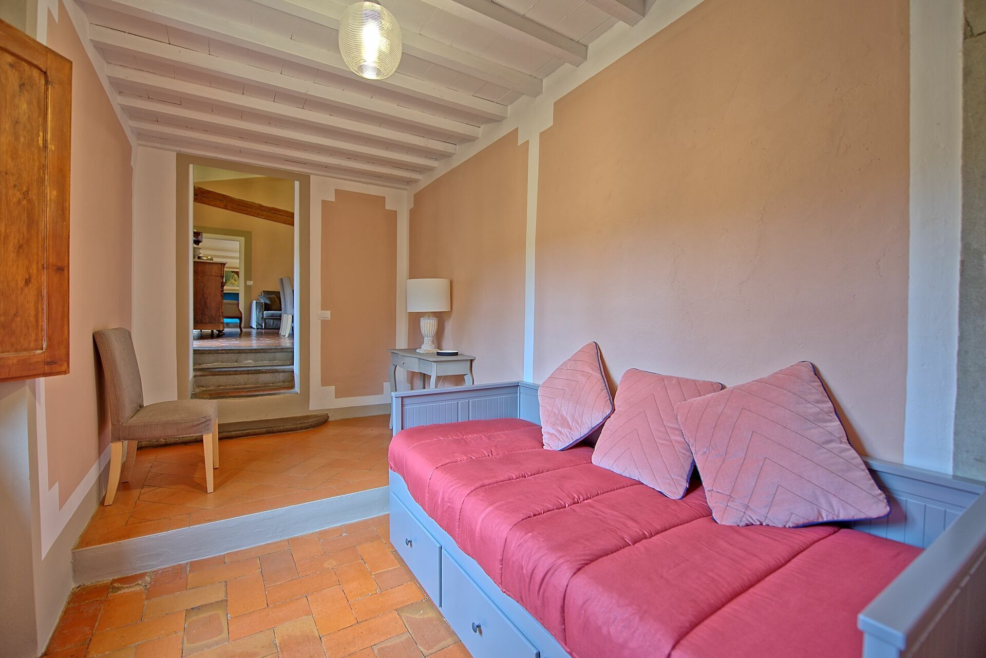 Une pièce confortable avec un lit, une chaise et une lampe.