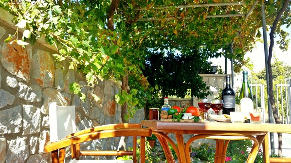 A wooden table set outdoors with a stone wall and greenery in the background.