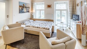 A modern bedroom with a large bed, two armchairs, a small table, and a TV. - ❤️ Cozy, Spacious, Quiet, Great Central Location (Praha 3)