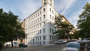 A multi-story building with a corner tower, surrounded by trees and parked cars. - ❤️ Cozy, Spacious, Quiet, Great Central Location (Praha 3)