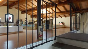 Une pièce mansardée spacieuse avec un plafond en bois et un escalier menant à l’étage inférieur.