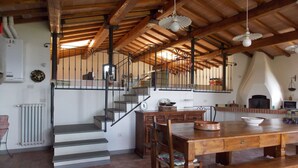 Une cuisine rustique avec une table en bois, des chaises et un escalier menant à un niveau supérieur.