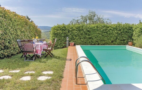 A backyard with a swimming pool, a dining table with chairs, and a view of the mountains. - Beautiful villa for 6 guests with WIFI, private pool, TV and panoramic view (Rignano Sull'arno)