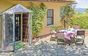 A patio with a table set for dining, a glass greenhouse, and climbing plants on a building. - Beautiful villa for 6 guests with WIFI, private pool, TV and panoramic view (Rignano Sull'arno)