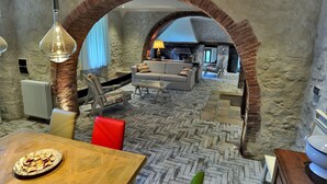 Ein rustikales Interieur mit freiliegenden Backsteinwänden, einem Fischgrätparkett und einer gemütlichen Sitzecke mit Sofa und Sesseln.